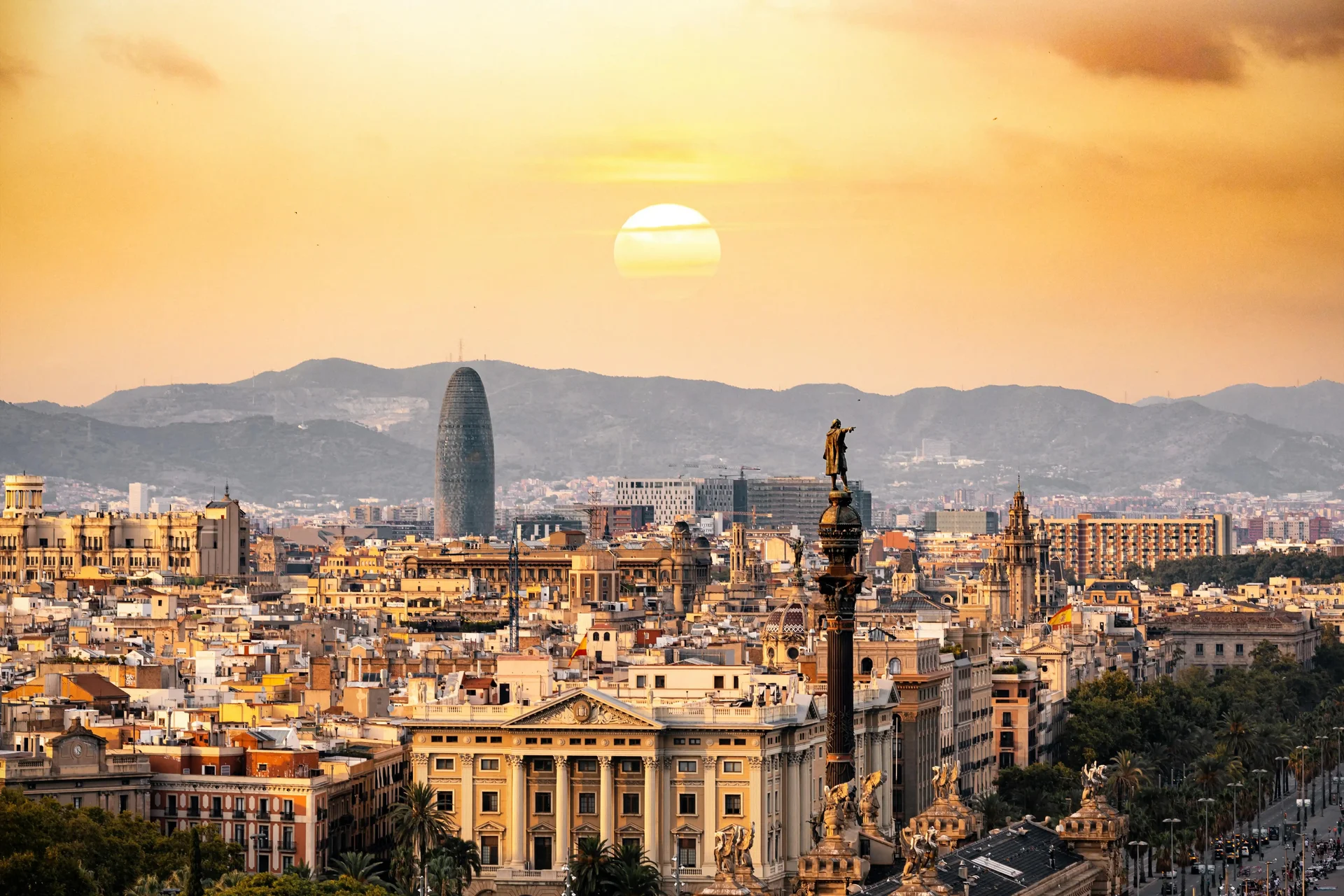 View of Barcelona at sunset with the Columbus statue and the Agbar Tower, a destination in Europe full of culture and history.
