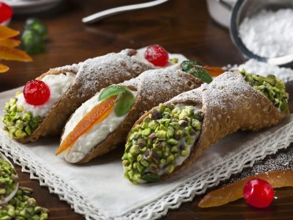 3 doces do tipo canolli, um de pistache, outro de creme outro de pistache e cereja