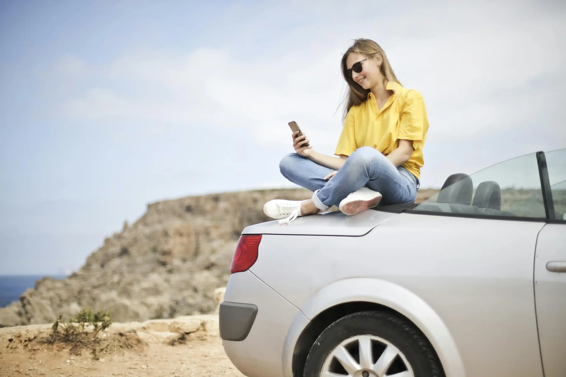 Jovem utilizando seu celular em um ponto remoto com internet de eSIM durante viagem em feriado.