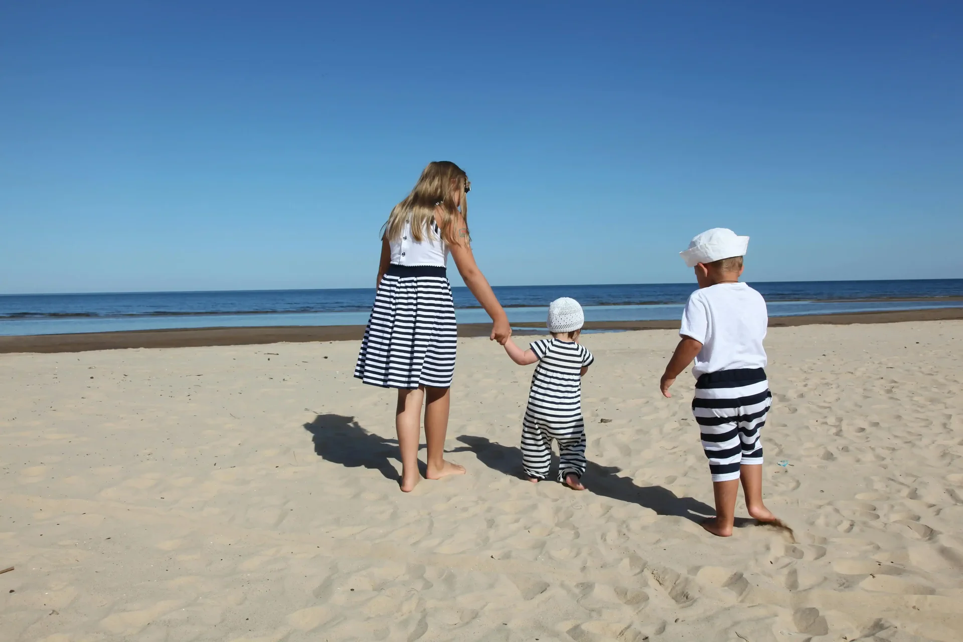 Uma mãe e seus dois filhos e uma praia durante viagem de feriado.