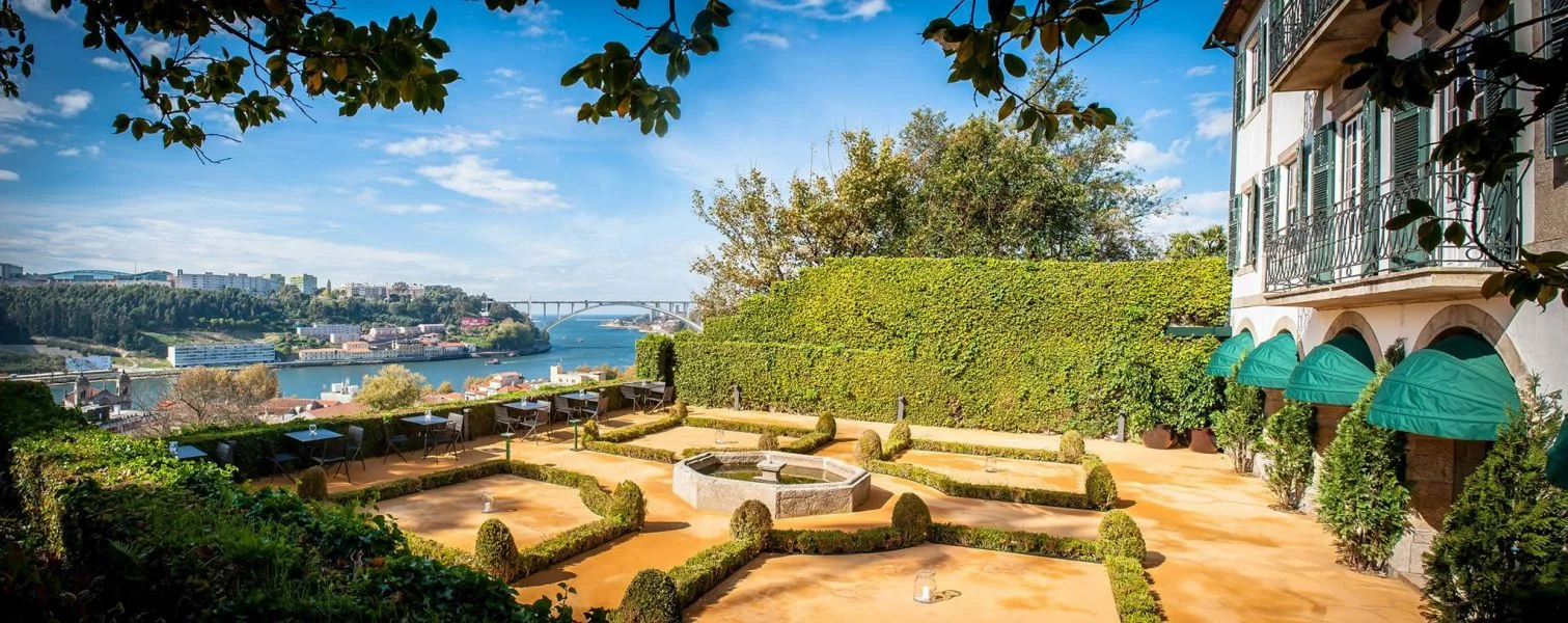 Patio com jardim ao centro, casa ao lado direito, e mar ao lado esquerdo
