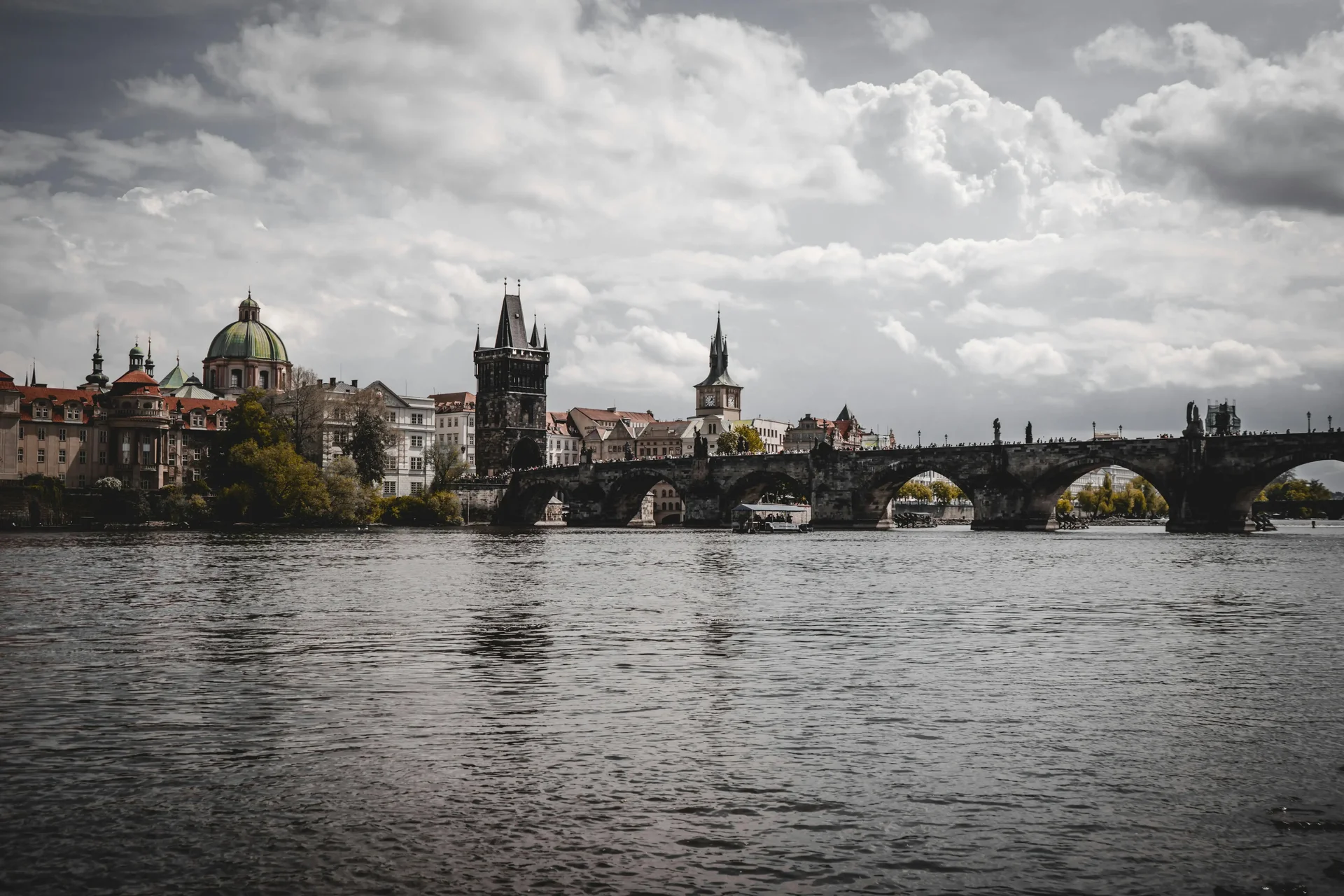 Ponte Carlos em Praga, com a arquitetura histórica ao fundo refletindo no rio Moldava.