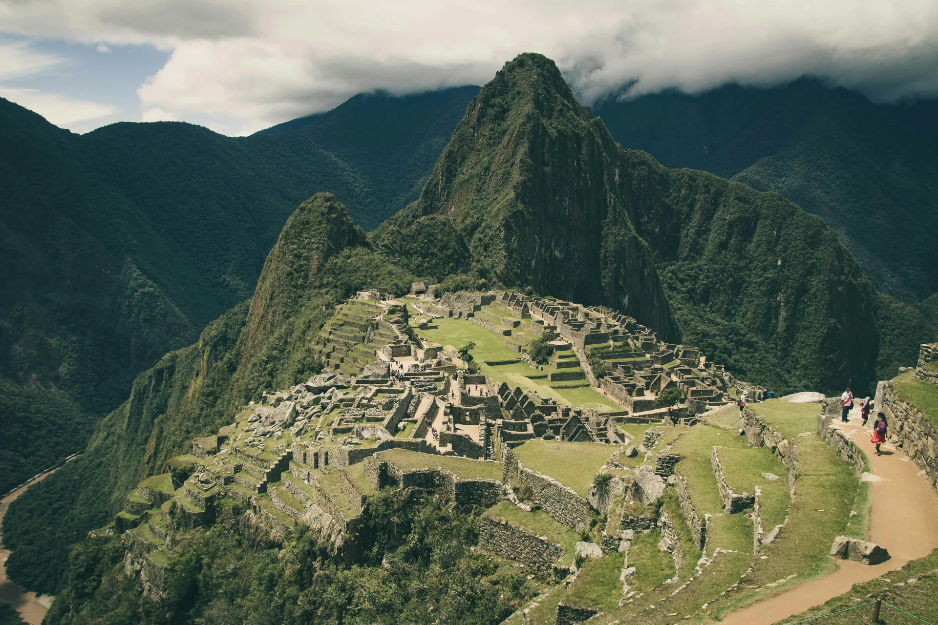 Vista panorâmica de Machu Picchu, Peru, com montanhas verdes ao fundo e ruínas antigas.