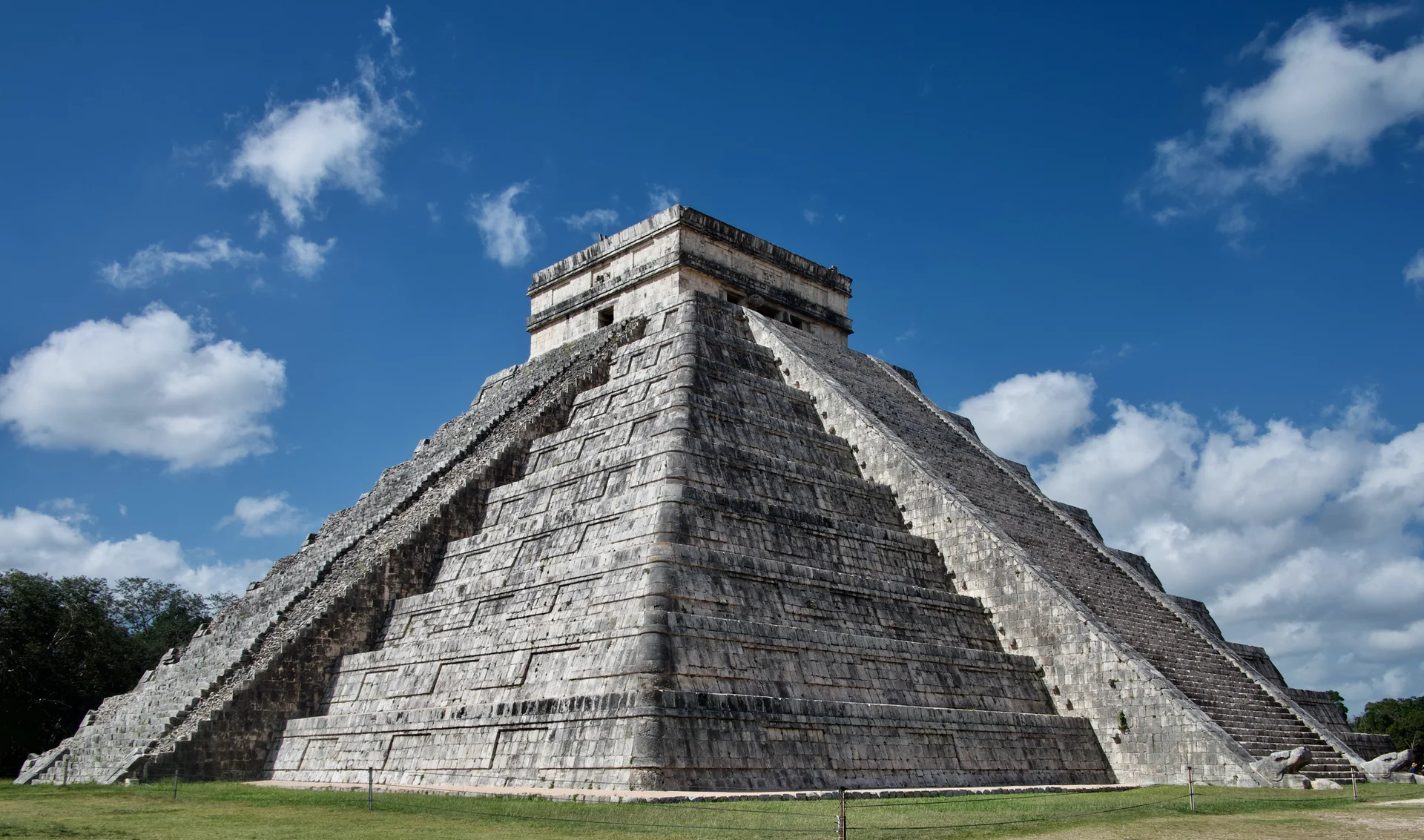 Pirâmide Maya ao centro, com ceu azul e nuvens brancas