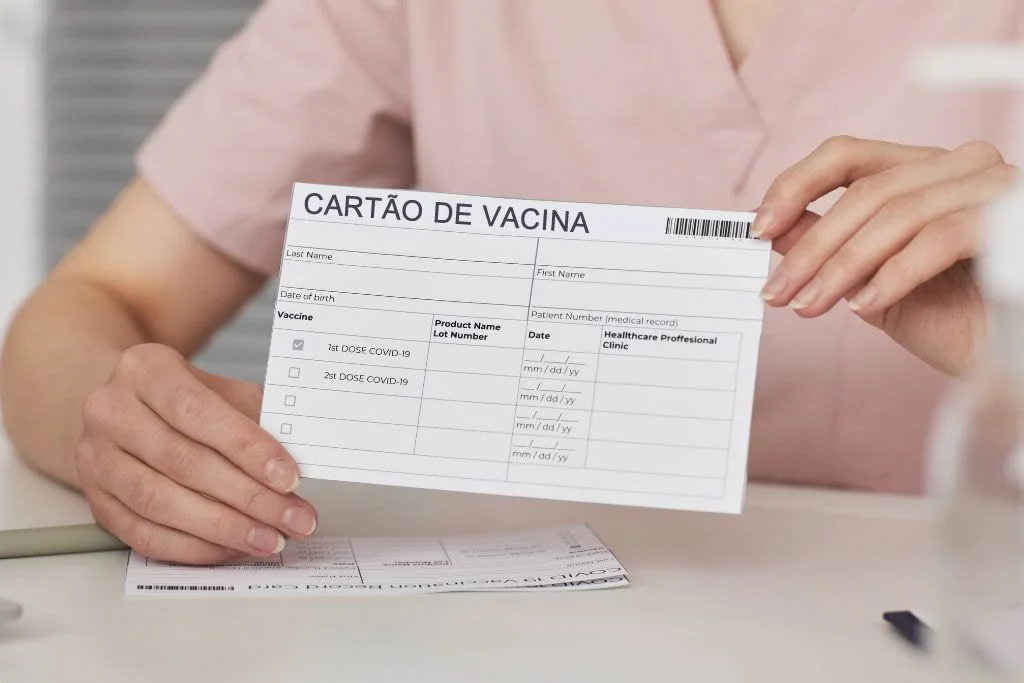 Cartão de vacinação em mãos, simbolizando a importância de estar em dia com as exigências médicas para viagens internacionais.