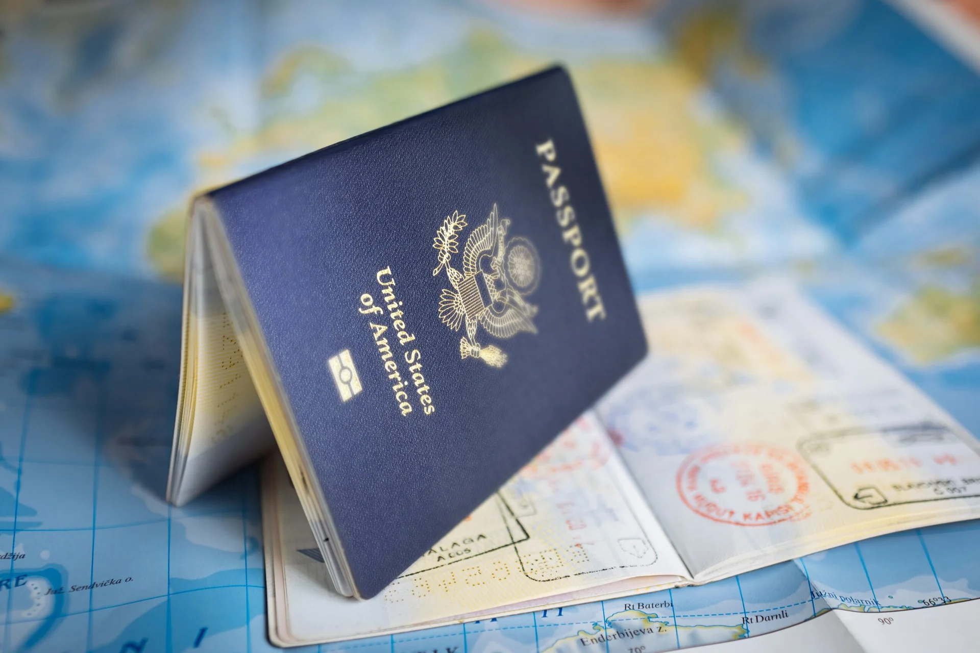 Passaporte dos Estados Unidos em destaque sobre um mapa com carimbos de viagem, representando documentação essencial para viagens internacionais.