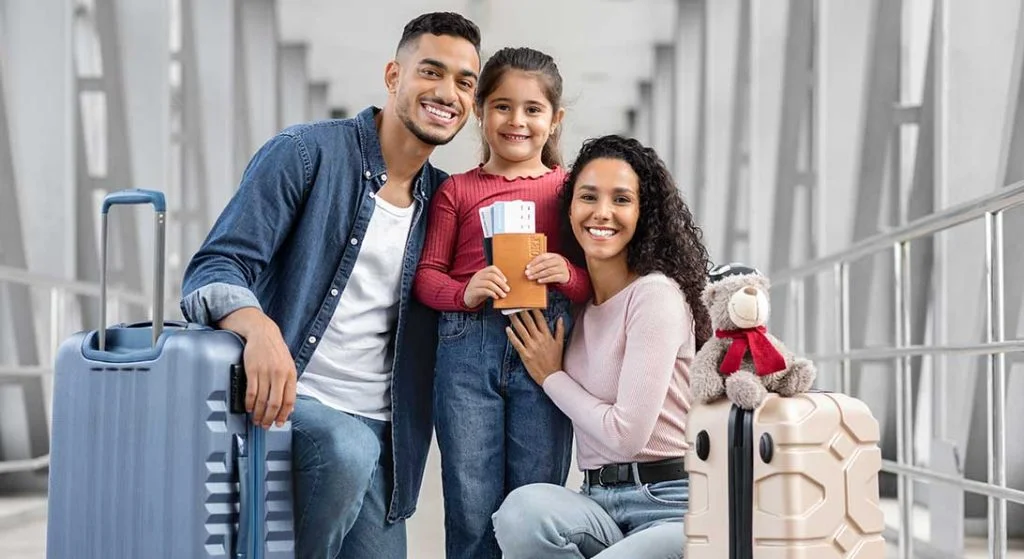 Família sorridente segurando passaportes no aeroporto, prontos para embarcar em viagem aos Estados Unidos.