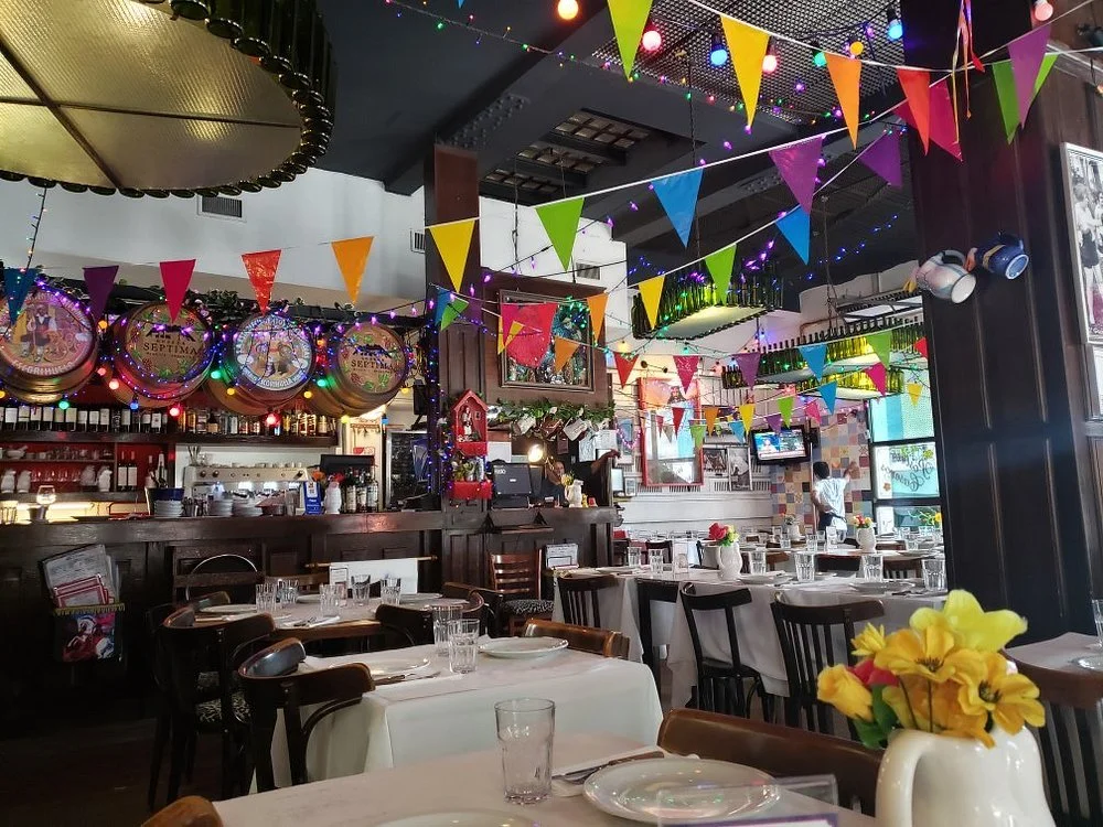 Ambiente de um restaurante típico, com mesas de madeira e pratos sendo servidos em um espaço informal.