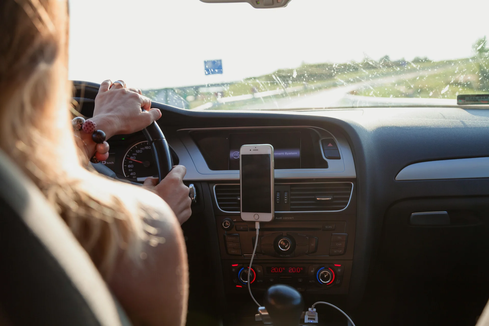 Mulher dirigindo com smartphone no suporte veicular.