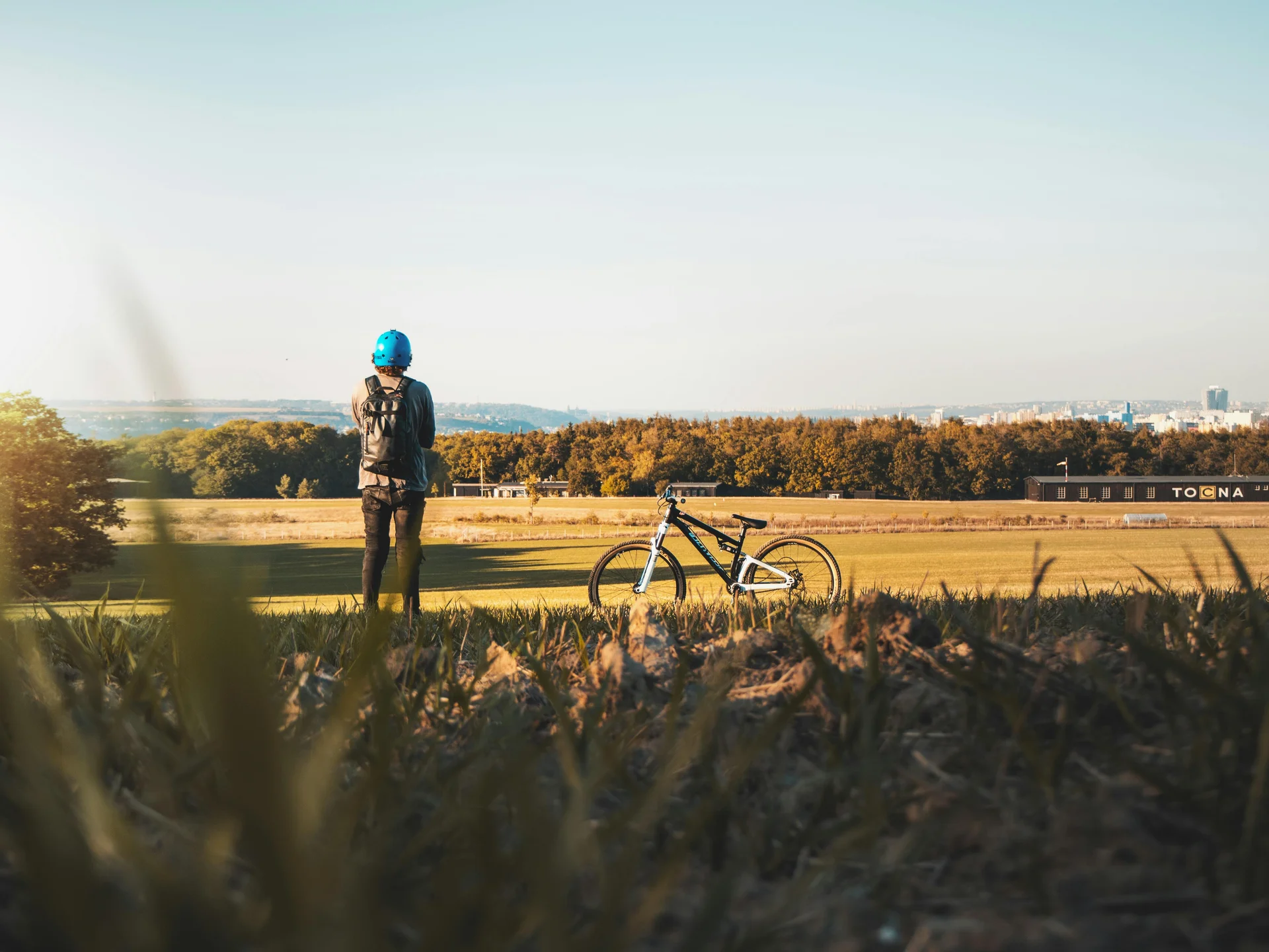 Homem olhando para campo ao lado de uma bicicleta.