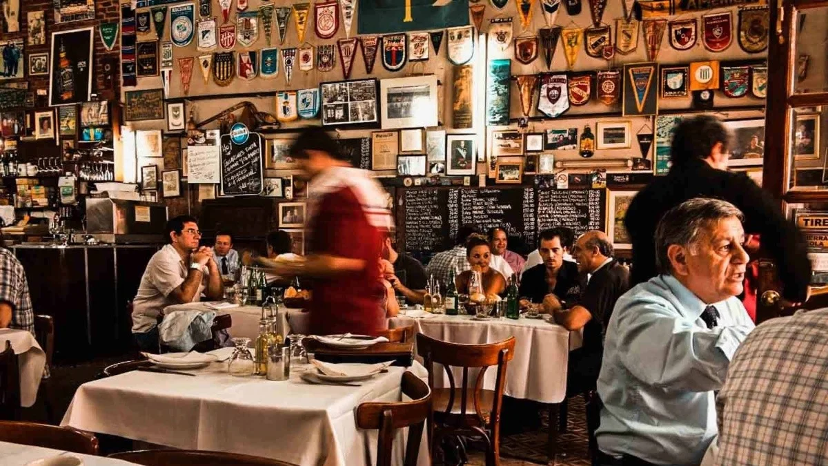 Restaurante com muitas obras de arte na parede, e pessoas comendo nas mesas